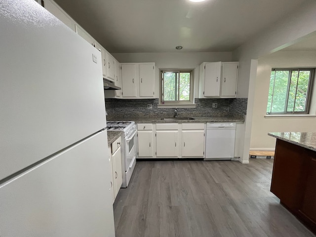 kitchen with dark stone counters, white appliances, sink, light hardwood / wood-style floors, and white cabinetry