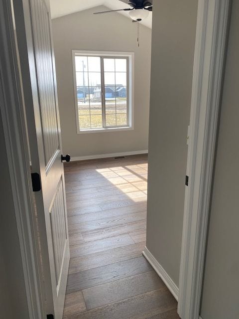 corridor with light wood-type flooring and lofted ceiling