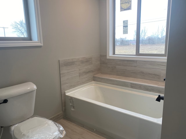 bathroom featuring a tub to relax in and toilet