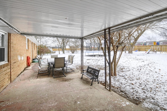 snow covered patio featuring a playground and a trampoline