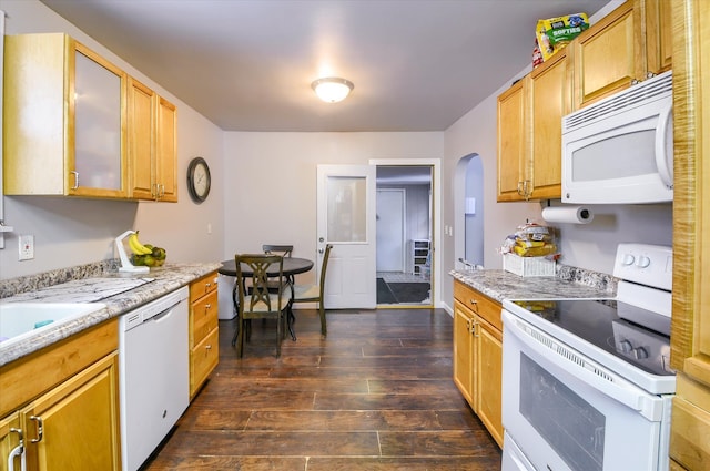 kitchen with heating unit, sink, dark hardwood / wood-style flooring, light stone countertops, and white appliances