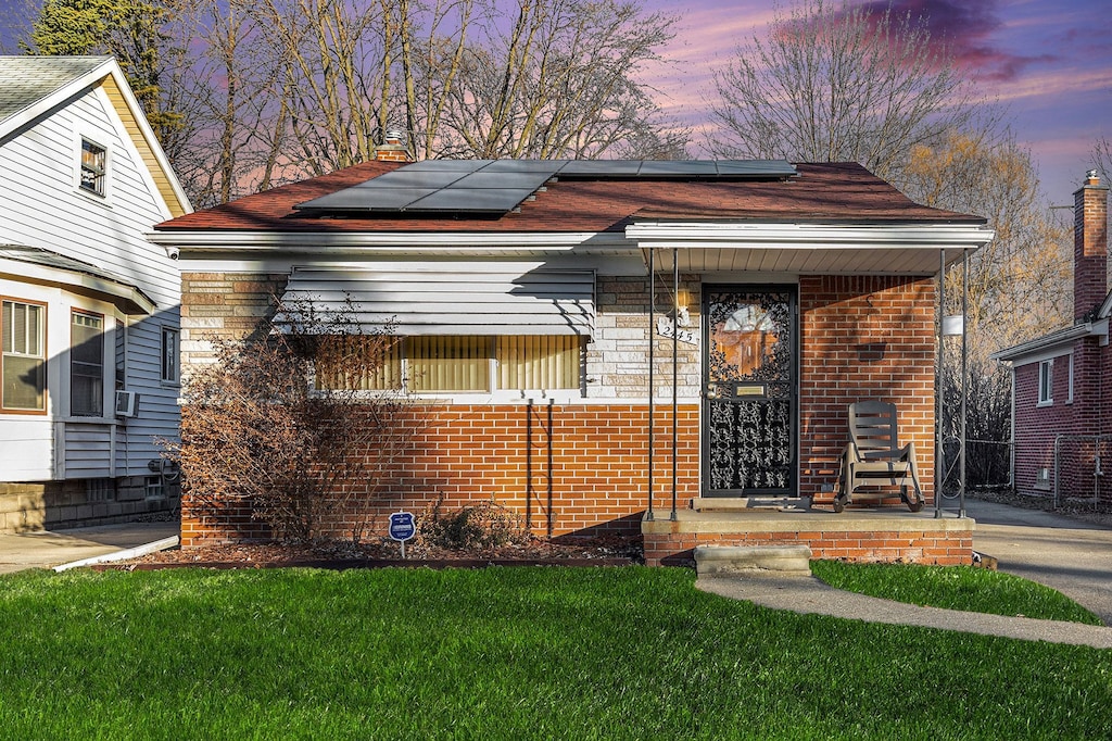 view of front of property featuring solar panels and a lawn