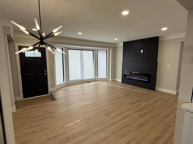 entryway featuring a large fireplace, baseboards, wood finished floors, an inviting chandelier, and recessed lighting