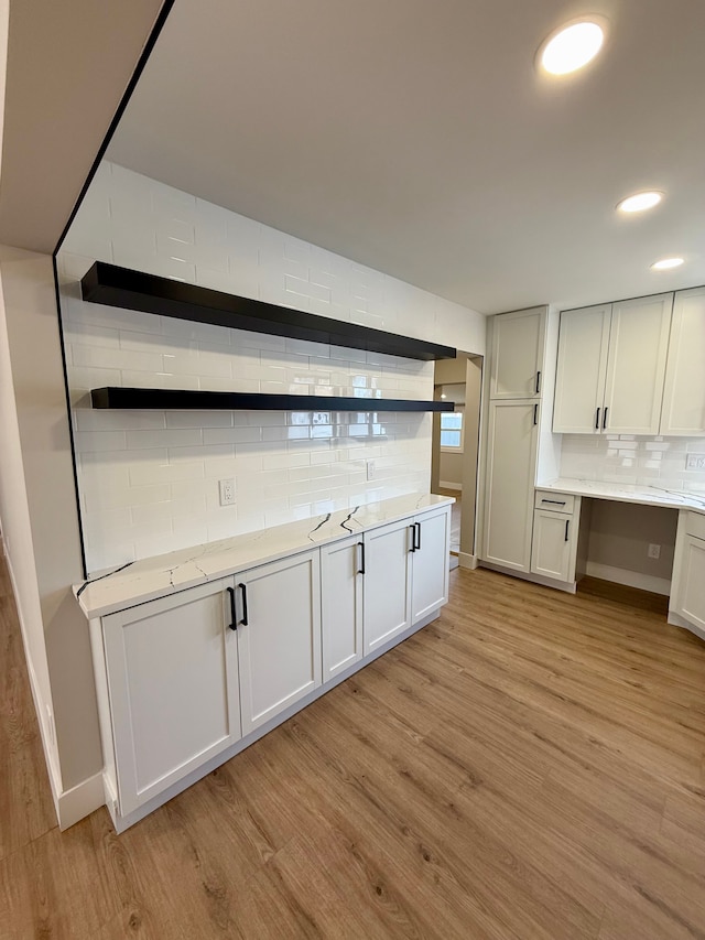 kitchen with light stone counters, tasteful backsplash, recessed lighting, light wood-style floors, and white cabinetry