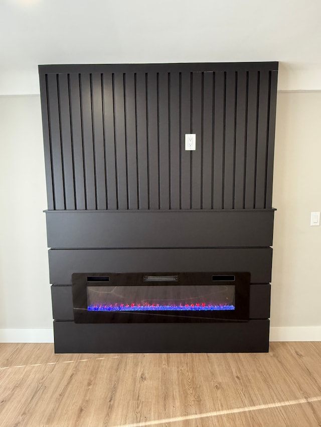 details featuring a large fireplace, wood finished floors, and baseboards