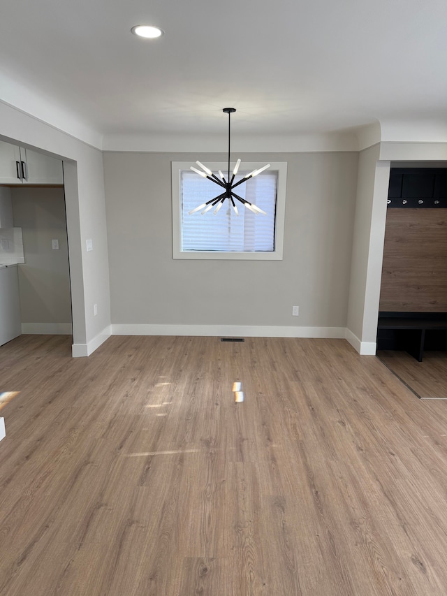 unfurnished dining area featuring visible vents, light wood-style flooring, and baseboards