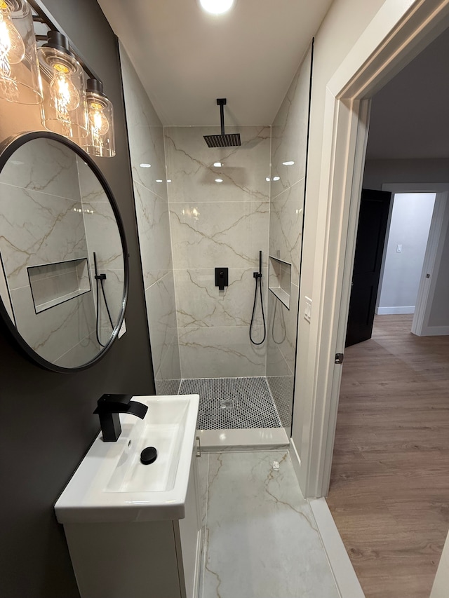 full bathroom featuring a sink, wood finished floors, and a marble finish shower