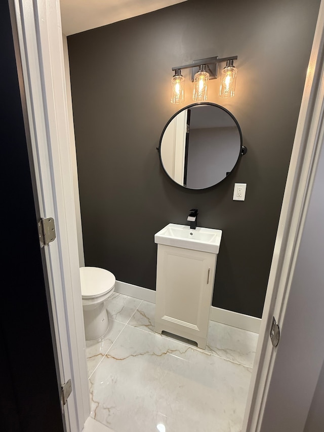 bathroom with toilet, marble finish floor, baseboards, and vanity