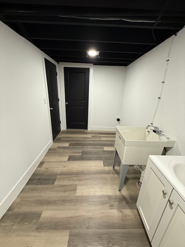 laundry area featuring light wood-type flooring, laundry area, a sink, and baseboards