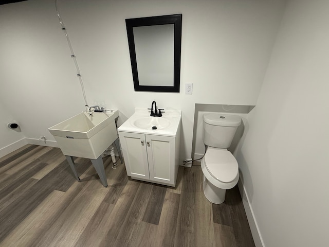 bathroom with vanity, wood finished floors, toilet, and baseboards