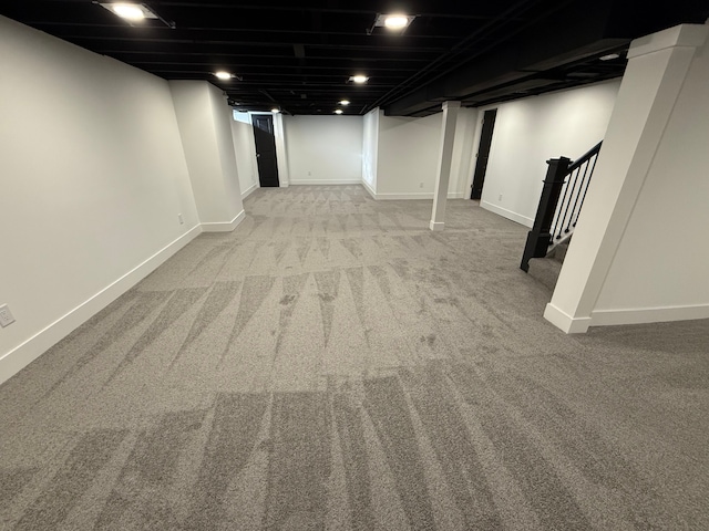 finished basement featuring stairway, carpet, and baseboards