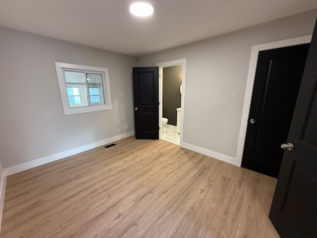 unfurnished bedroom featuring visible vents, connected bathroom, light wood-style flooring, and baseboards