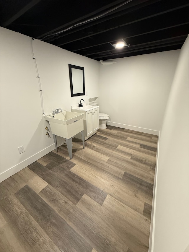 interior space with a sink, wood finished floors, and baseboards