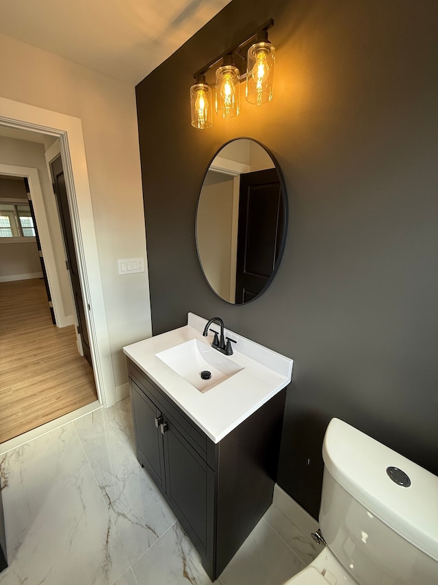 bathroom with toilet, marble finish floor, baseboards, and vanity