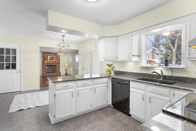 kitchen with kitchen peninsula, a brick fireplace, sink, black dishwasher, and white cabinetry