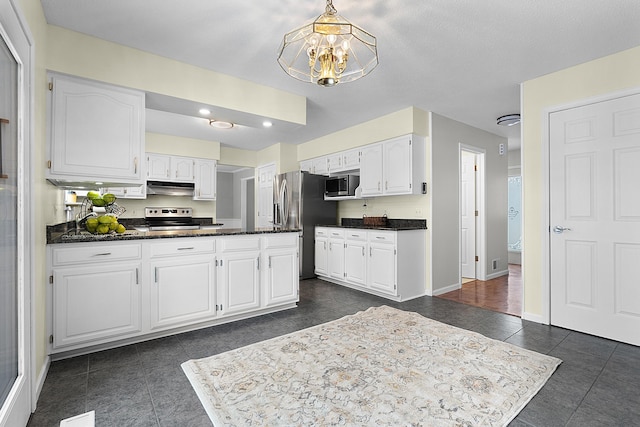 kitchen featuring white cabinets, dark tile patterned flooring, a notable chandelier, and appliances with stainless steel finishes