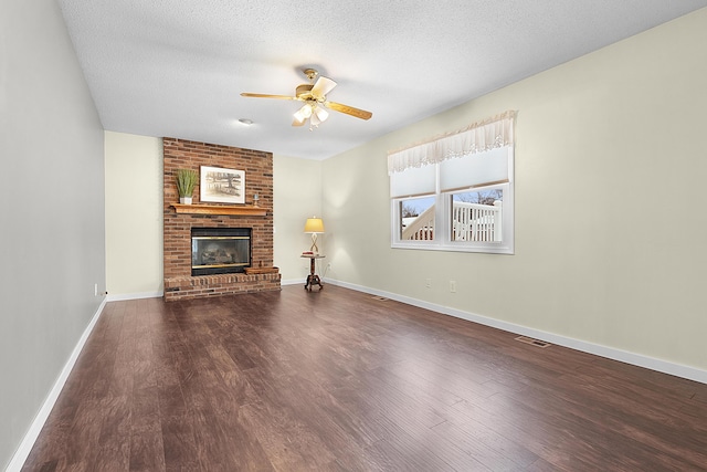 unfurnished living room featuring ceiling fan, a fireplace, dark hardwood / wood-style floors, and a textured ceiling