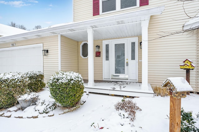 snow covered property entrance featuring a garage