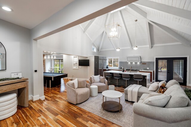 living room with high vaulted ceiling, billiards, beamed ceiling, hardwood / wood-style flooring, and french doors