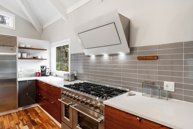 kitchen with vaulted ceiling with beams, premium appliances, backsplash, dark hardwood / wood-style floors, and wall chimney range hood