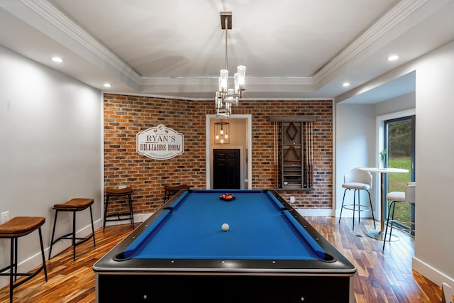 recreation room with hardwood / wood-style flooring, ornamental molding, and brick wall