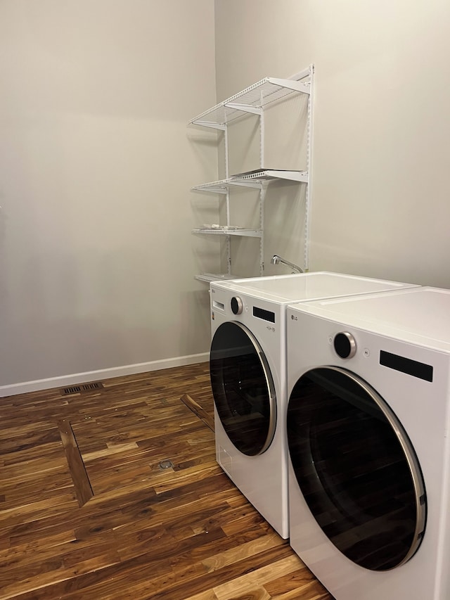 clothes washing area with washer and dryer and dark wood-type flooring