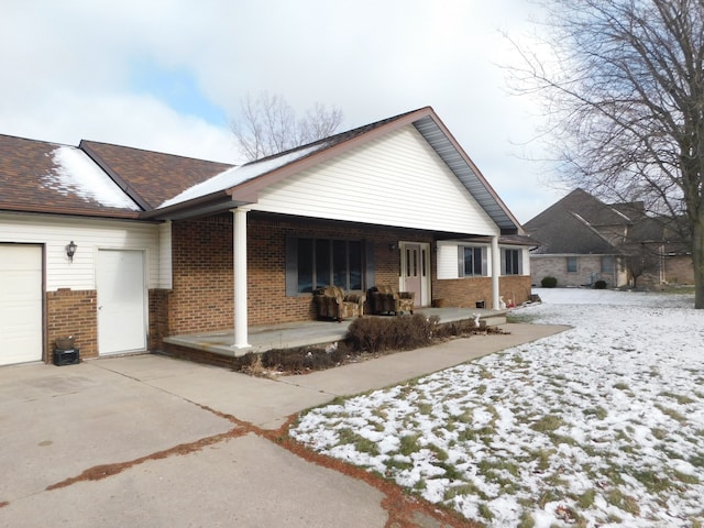 view of snowy exterior featuring a porch and a garage