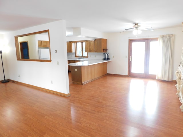 kitchen featuring sink, ceiling fan, white fridge, light hardwood / wood-style floors, and kitchen peninsula