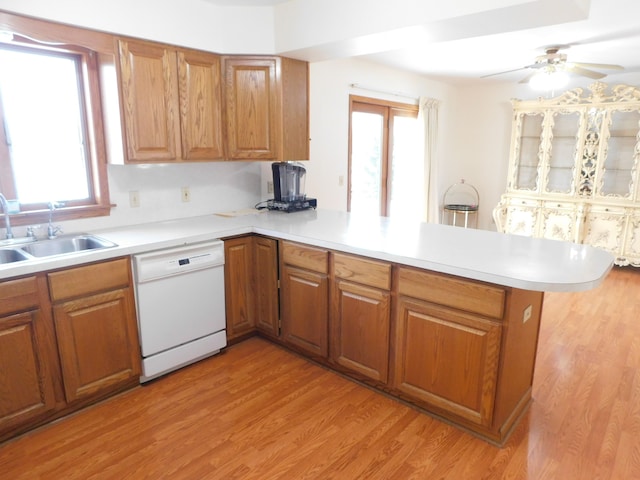 kitchen with kitchen peninsula, white dishwasher, a wealth of natural light, and sink