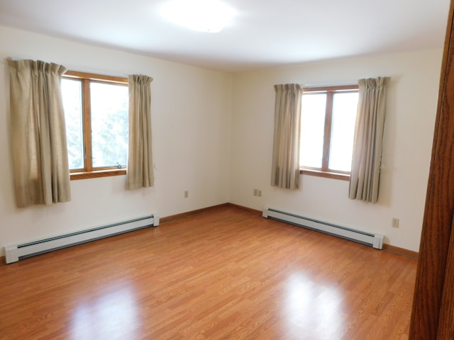 unfurnished room with a wealth of natural light, light hardwood / wood-style flooring, and a baseboard heating unit