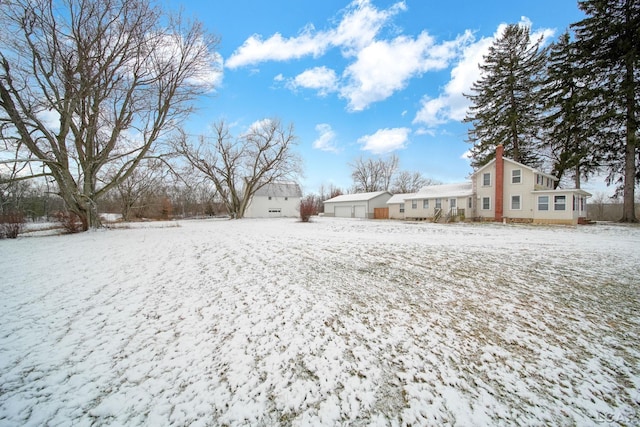 yard covered in snow featuring a garage and an outdoor structure