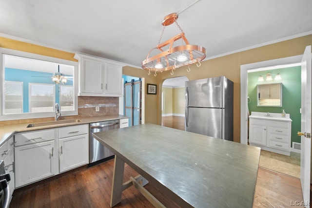 kitchen with decorative light fixtures, sink, white cabinetry, and stainless steel appliances