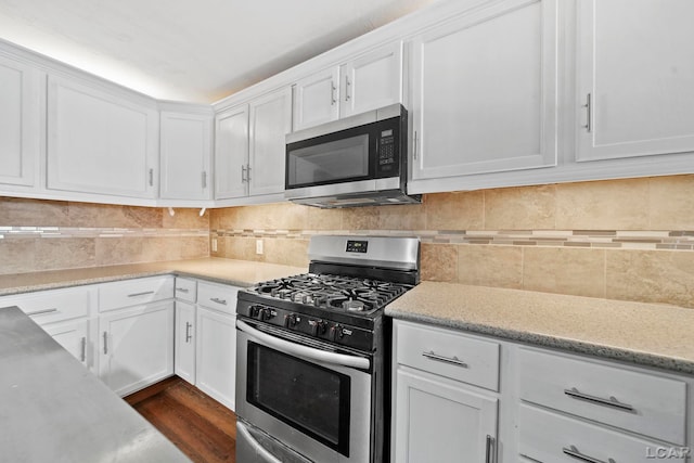 kitchen with white cabinets, dark hardwood / wood-style floors, stainless steel appliances, and tasteful backsplash