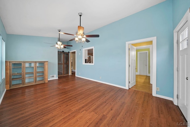 unfurnished living room with a barn door, vaulted ceiling, ceiling fan, and dark wood-type flooring