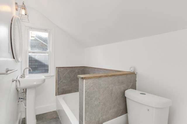 bathroom with toilet, lofted ceiling, and a tub to relax in