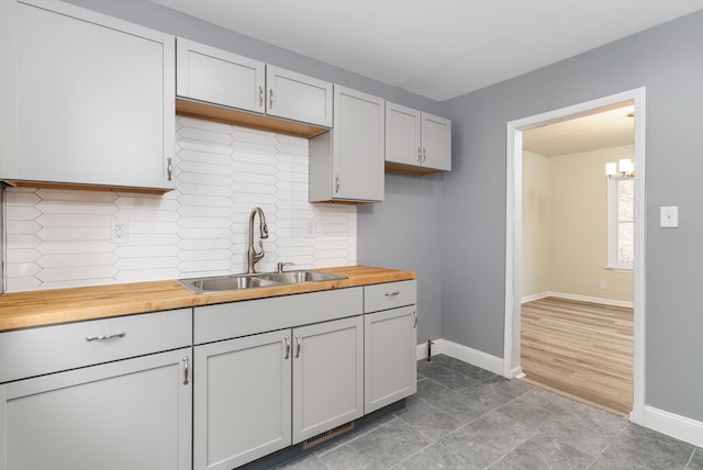 kitchen featuring butcher block countertops, white cabinetry, and sink