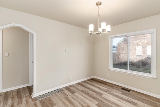 empty room featuring light hardwood / wood-style flooring and an inviting chandelier