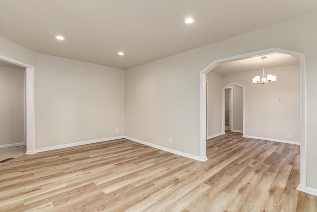 unfurnished room with an inviting chandelier and light hardwood / wood-style flooring