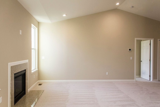 unfurnished living room with a high end fireplace, light colored carpet, plenty of natural light, and lofted ceiling