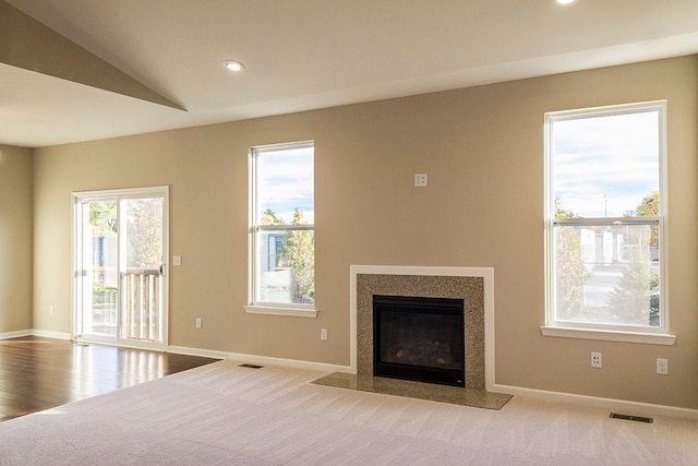 unfurnished living room with plenty of natural light, light colored carpet, and lofted ceiling