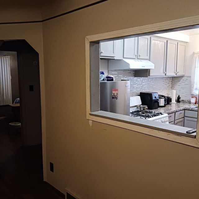 kitchen with white cabinets, decorative backsplash, refrigerator, and white range with gas stovetop