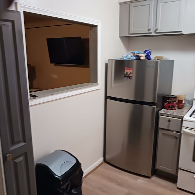 kitchen featuring gray cabinets, stainless steel fridge, white electric stove, and light hardwood / wood-style flooring