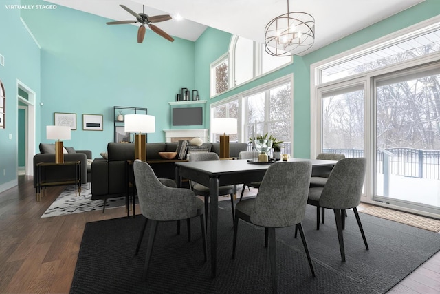 dining room with hardwood / wood-style flooring, ceiling fan with notable chandelier, and a towering ceiling