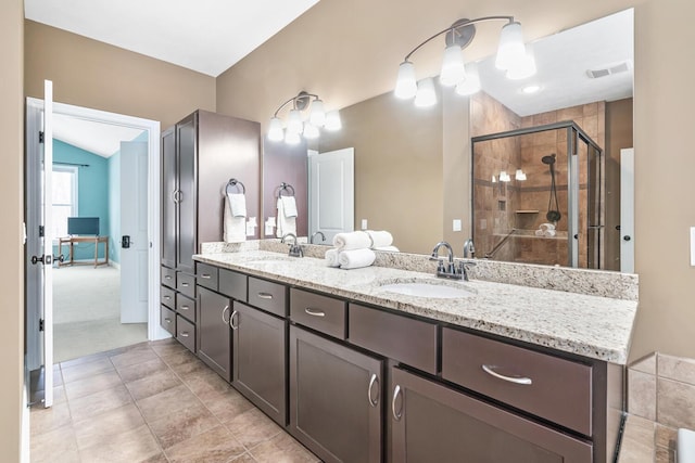 bathroom with vanity, a shower with shower door, and vaulted ceiling