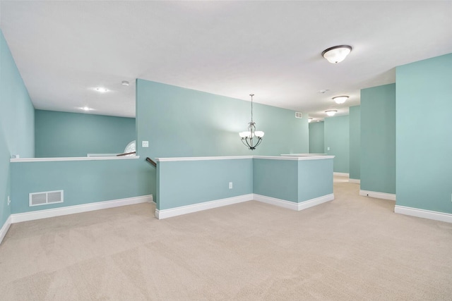 carpeted spare room featuring an inviting chandelier