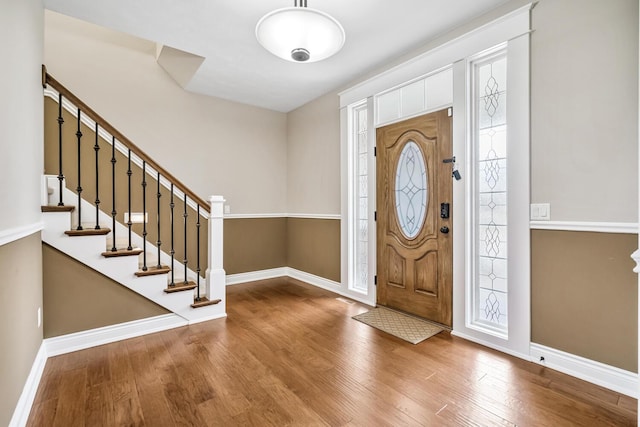 foyer featuring stairway, baseboards, and wood finished floors