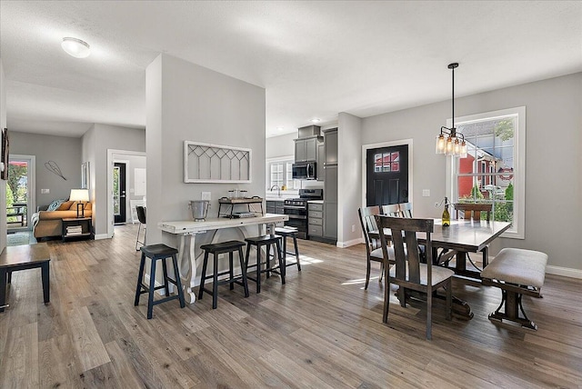 dining room featuring sink, light wood-type flooring, and a notable chandelier