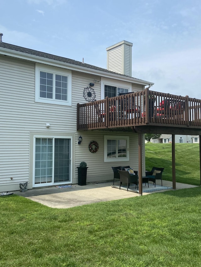 back of property with a deck, a patio area, and a lawn