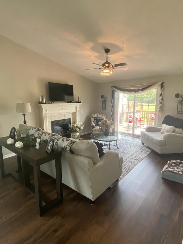 living room with a tile fireplace, ceiling fan, and dark wood-type flooring