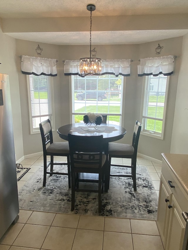 tiled dining area featuring plenty of natural light, a textured ceiling, and an inviting chandelier